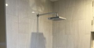 View of shower with modern showerhead and subway style wall panels.