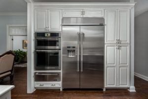 White kitchen cabinets surrounding a side-by-side fridge and modern oven.